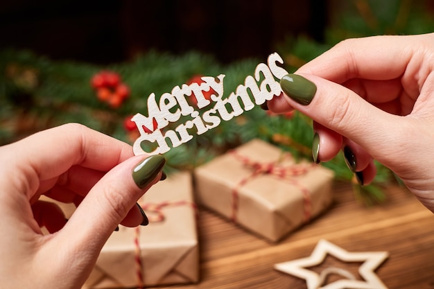 La ragazza tiene in mano la scritta Buon Natale sullo sfondo degli accessori natalizi