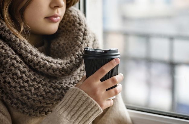 La ragazza tiene in mano un bicchiere di carta con il caffè