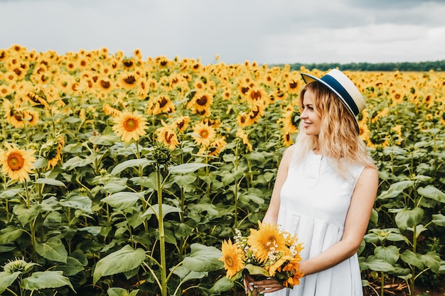 La ragazza tiene in mano un bouquet di girasoli nel campo di girasoli.