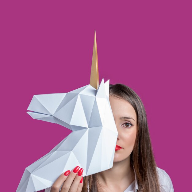 La ragazza tiene in mano un modello di papercraft 3d bianco del concetto di arte minima di unicorno