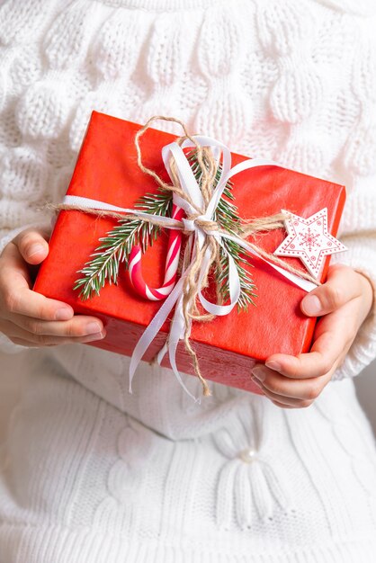 La ragazza tiene in mano un regalo di Natale avvolto in carta regalo rossa.