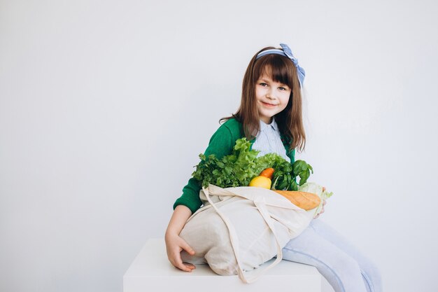 La ragazza tiene in mano una borsa ecologica con verdure, verdure senza plastica con sfondo. Zero sprechi, senza plastica Concetto ecologico.