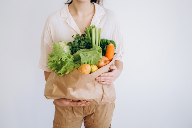 La ragazza tiene in mano una borsa ecologica con verdure, verdure senza plastica con sfondo. Zero sprechi, senza plastica Concetto ecologico.