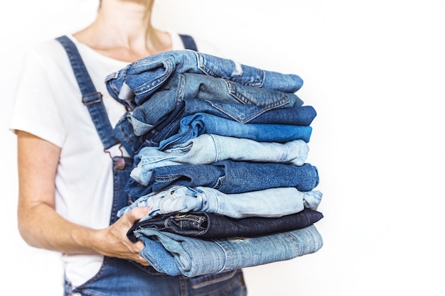 La ragazza tiene in mano una pila di jeans. pulizia nell'armadio.