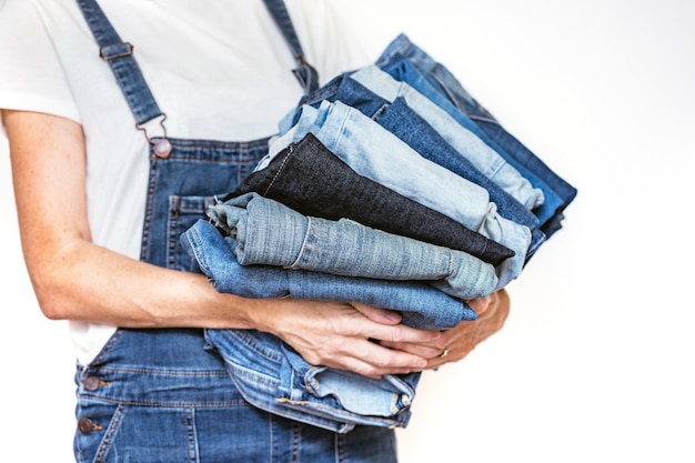 La ragazza tiene in mano una pila di jeans. pulizia nell'armadio.