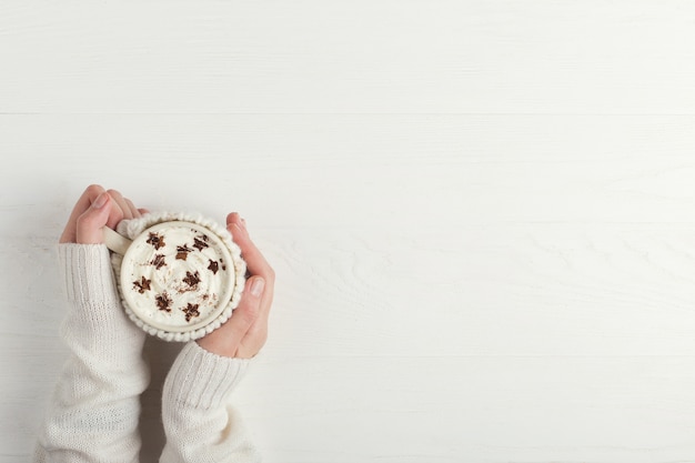 La ragazza tiene in mano una tazza di bevanda invernale calda, con panna montata