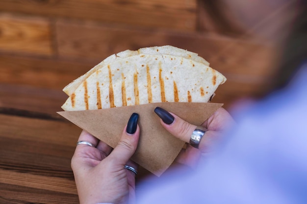 La ragazza tiene in mano uno spuntino di tortilla sullo sfondo di una caffetteria