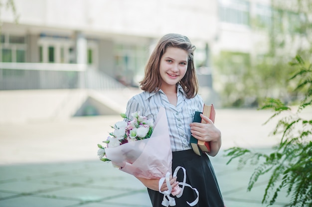 La ragazza tiene libri e un mazzo di fiori in mano per l'insegnante