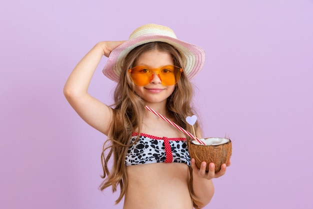 La ragazza tiene tra le mani un cocktail versato in una noce di cocco.