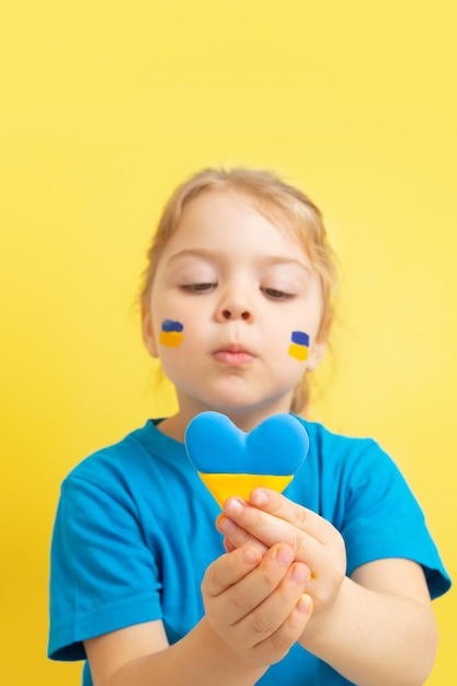 La ragazza tiene un cuore di colore giallo e blu della bandiera ucraina