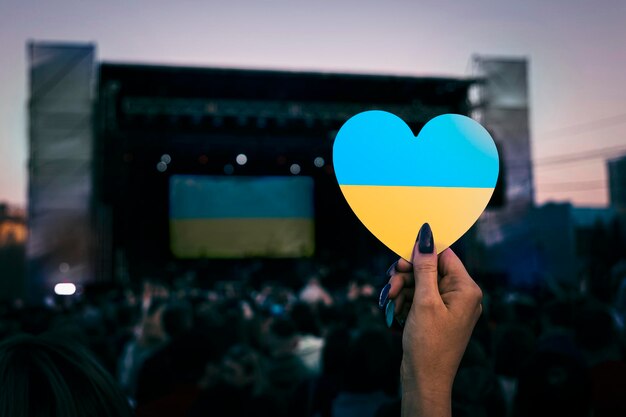 La ragazza tiene un cuore in mano con i colori della bandiera ucraina in segno di solidarietà con il regime in Ucraina Concerto politico di strada in Europa