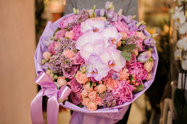 La ragazza tiene un mazzo di diversi fiori rosa e viola, tra cui orchidee