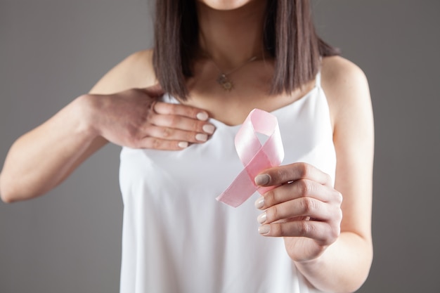 La ragazza tiene un nastro rosa su un grigio