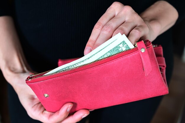 La ragazza tiene un portafogliodollari nelle sue mani il portafoglio pieno di dollari paga il conto