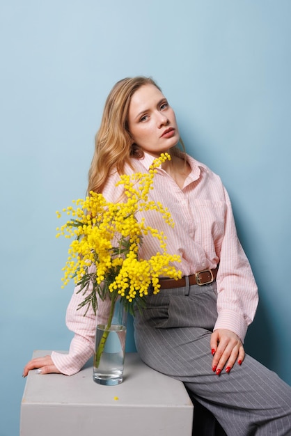 la ragazza tiene un ramo di mimosa in mano e lo mette nel concetto di sorgente d'acqua