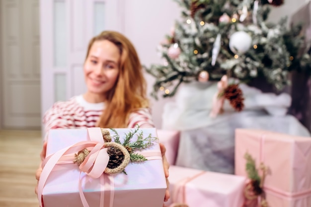 La ragazza tiene un regalo, albero di Natale, scatola rosa con un regalo