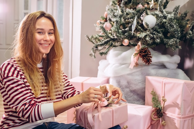La ragazza tiene un regalo, albero di Natale, scatola rosa con un regalo