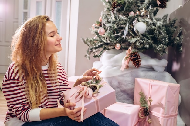 La ragazza tiene un regalo, albero di Natale, scatola rosa con un regalo