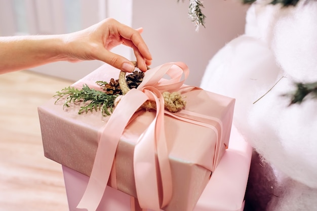 La ragazza tiene un regalo, albero di Natale, scatola rosa con un regalo