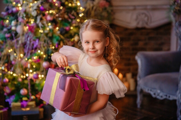 la ragazza tiene un regalo vicino all'albero di Natale