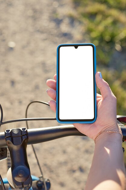 La ragazza tiene un telefono cellulare in sella alla bicicletta. Modello