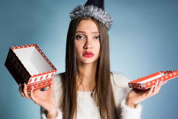 La ragazza triste con un cappello festivo ha ricevuto una scatola vuota per il nuovo anno