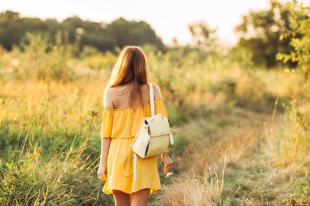 La ragazza va in campo e si è voltata verso la telecamera e lo zaino sulle spalle