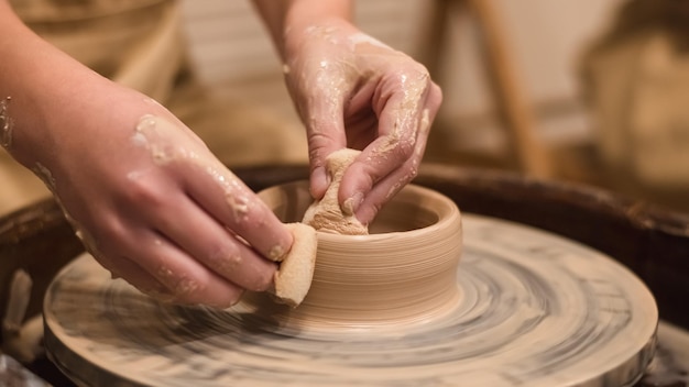 La ragazza vasaio lavora sul tornio del vasaio realizzando vasi di ceramica in argilla nel laboratorio di ceramica Concetto di arte e hobby