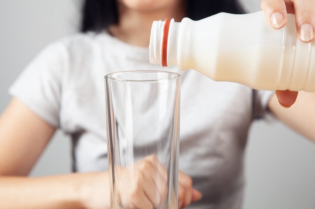 La ragazza versa il latte in un bicchiere