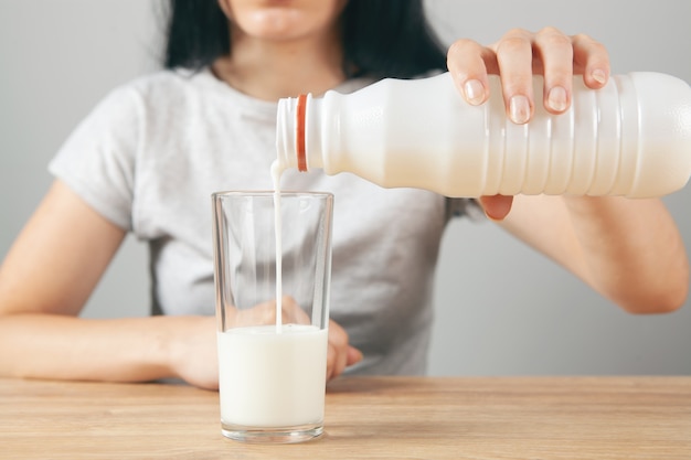 La ragazza versa il latte in un bicchiere