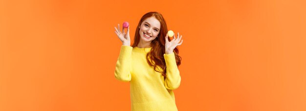 La ragazza vuole condividere il dessert tenendo due macaron e sorridendo suggerisce di mordere con un bel sorriso inclinandolo