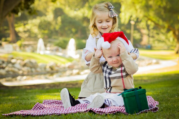 La ragazzina cerca di mettere il cappello di Babbo Natale al fratello piccolo