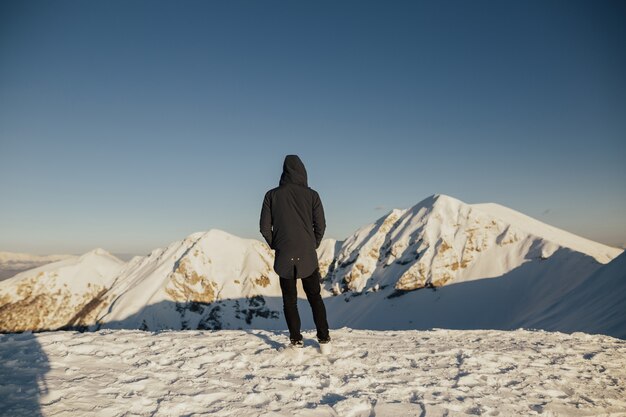 La retrovisione dell'uomo con sta guardando la natura incredibile nella montagna innevata.