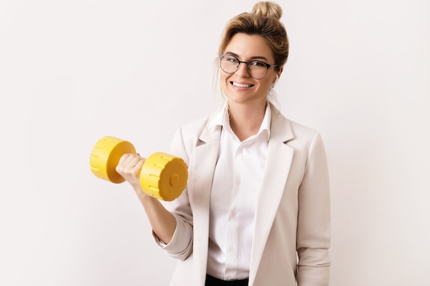 La riuscita donna felice di affari sta sollevando il dumbbell pesante. Concetto di avanzamento di carriera e duro lavoro.