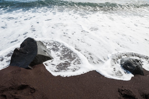 La sabbia nera e l'onda in riva al mare