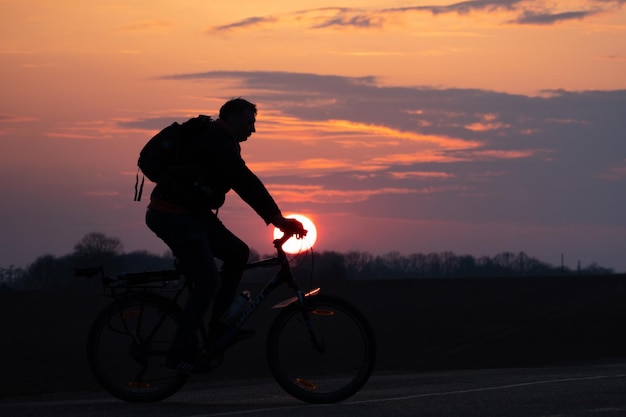 La sagoma di un ciclista sullo sfondo del sole e il bel cielo La sagoma di un uomo in sella a una bicicletta sullo sfondo del tramonto