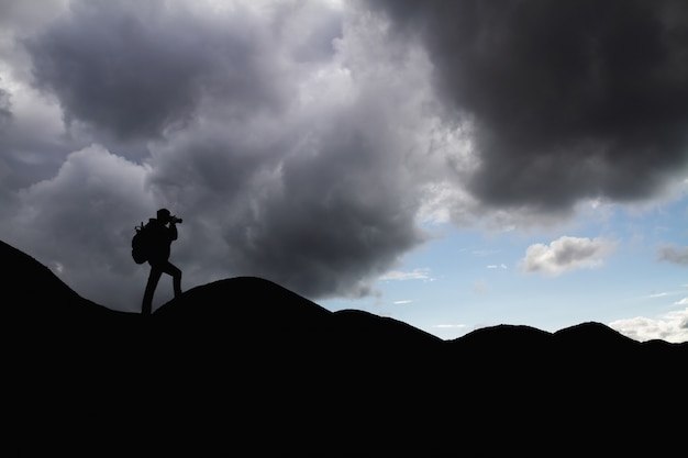 La sagoma di un uomo con lo zaino in montagna sta fotografando il paesaggio