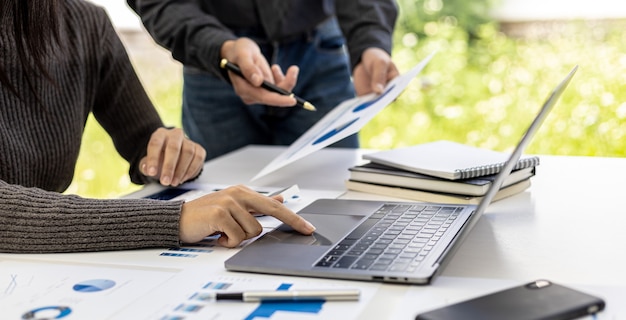 La sala conferenze ha due uomini d'affari che si incontrano, un uomo d'affari che usa un laptop e l'altro che esamina i documenti finanziari dell'azienda. Concetto di incontro per riassumere le finanze aziendali.