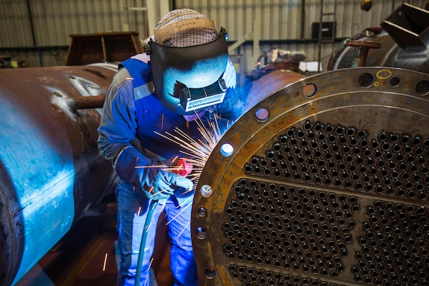La saldatura del metallo del lavoratore maschio fa parte della costruzione della conduttura della flangia di scambio termico del macchinario petrolio e gas