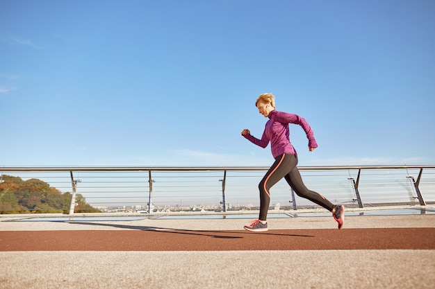 La salute arriva per la prima volta in una foto a figura intera di una donna matura attiva motivata in abbigliamento sportivo che corre all'aperto