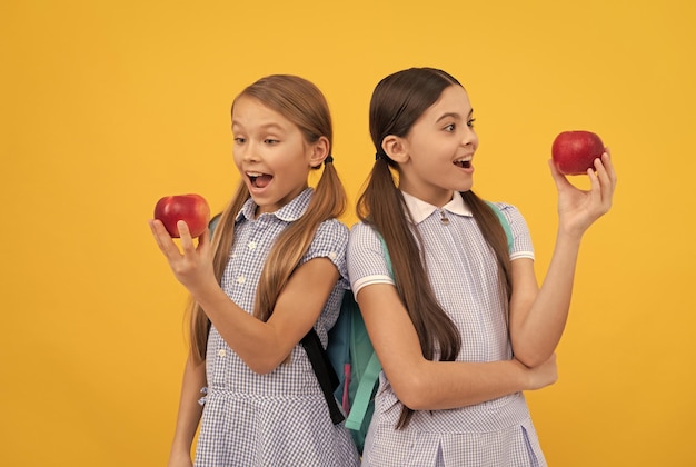 La salute nascosta nelle mele I bambini sorpresi guardano le mele sullo sfondo giallo Mangia più frutta