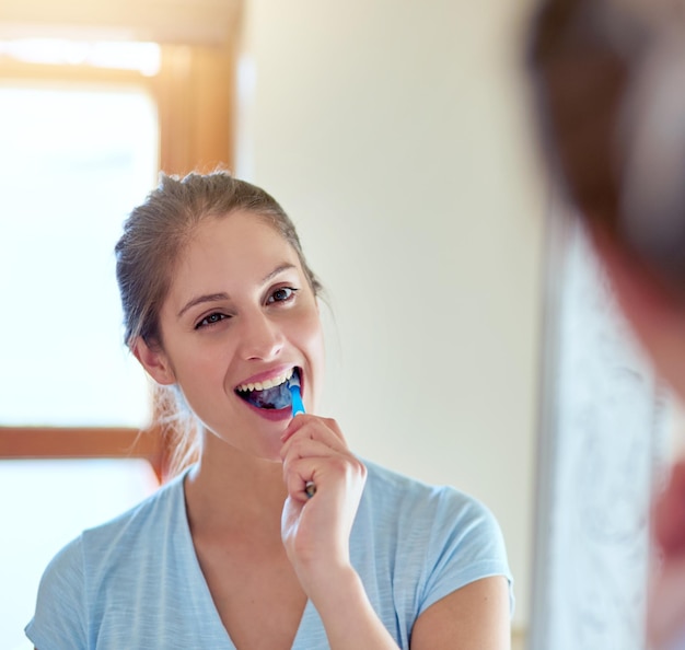 La salute orale riflette la tua salute generale Inquadratura ritagliata di una giovane donna che si lava i denti in uno specchio