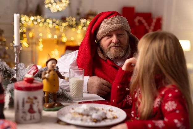 La santa allegra si siede nella casa al concetto di natale della tavola