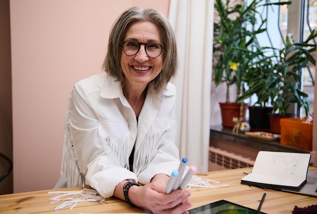 La sarta del sarto del sarto del progettista della donna caucasica sorridente sicura felice lavora sui nuovi vestiti nello studio di progettazione della moda L'impresa professionale creativa avvia il concetto di lavoro autonomo