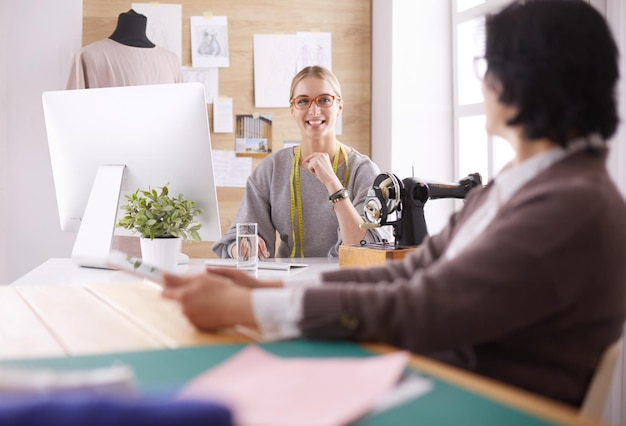 La sarta femminile sta comunicando con il potenziale cliente in merito all'abito su misura nel laboratorio di cucito