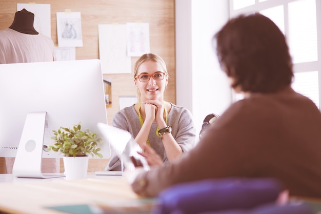 La sarta femminile sta comunicando con il potenziale cliente in merito all'abito su misura nel laboratorio di cucito