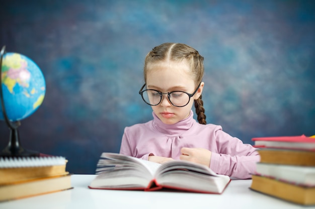 La scolara primaria sveglia ha letto il libro di testo fa i compiti