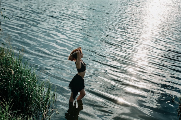 La seducente donna guerriera si erge al tramonto tra le onde del fiume come simbolo del femminile.