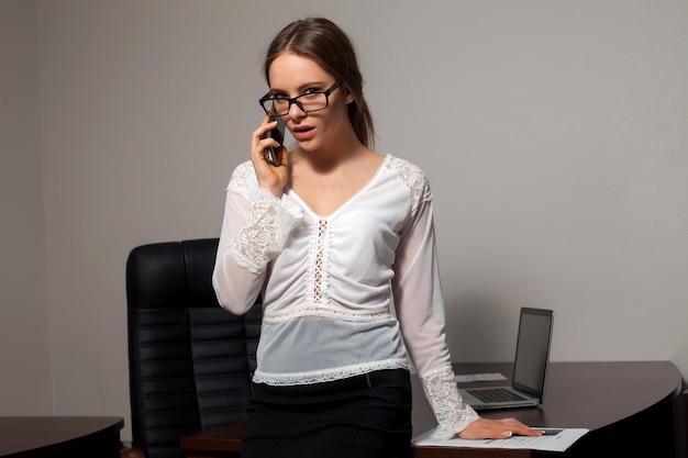 La segretaria intelligente sta rispondendo a una telefonata di lavoro in piedi in ufficio