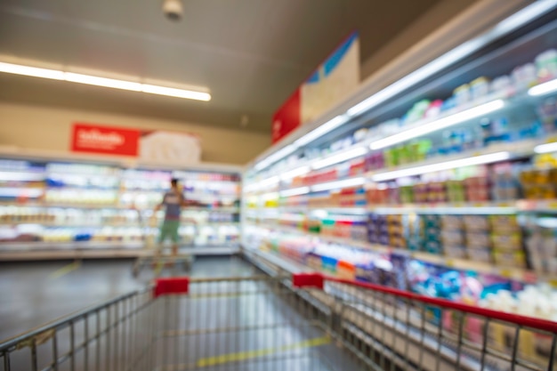 La sfocatura sfocata della bevanda femminile latte cibo acquisto carrello spesa messo su uno scaffale presso la bevanda nel supermercato.